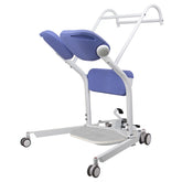 Manual sit-to-stand patient lift with adjustable base, blue pivoting seat pads, padded knee support, dual grab bars, foot platform, and four caster wheels.