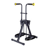 Black folding arm and leg exerciser with foam hand grips, yellow handle ends, foot pedals, and a wide floor base on a white background.
