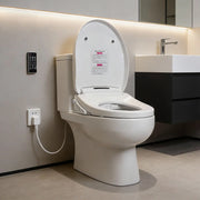 Side-angle view of a white electric bidet toilet seat installed in a bathroom, showing the open lid, elongated seat, side controls, and wall-mounted remote.