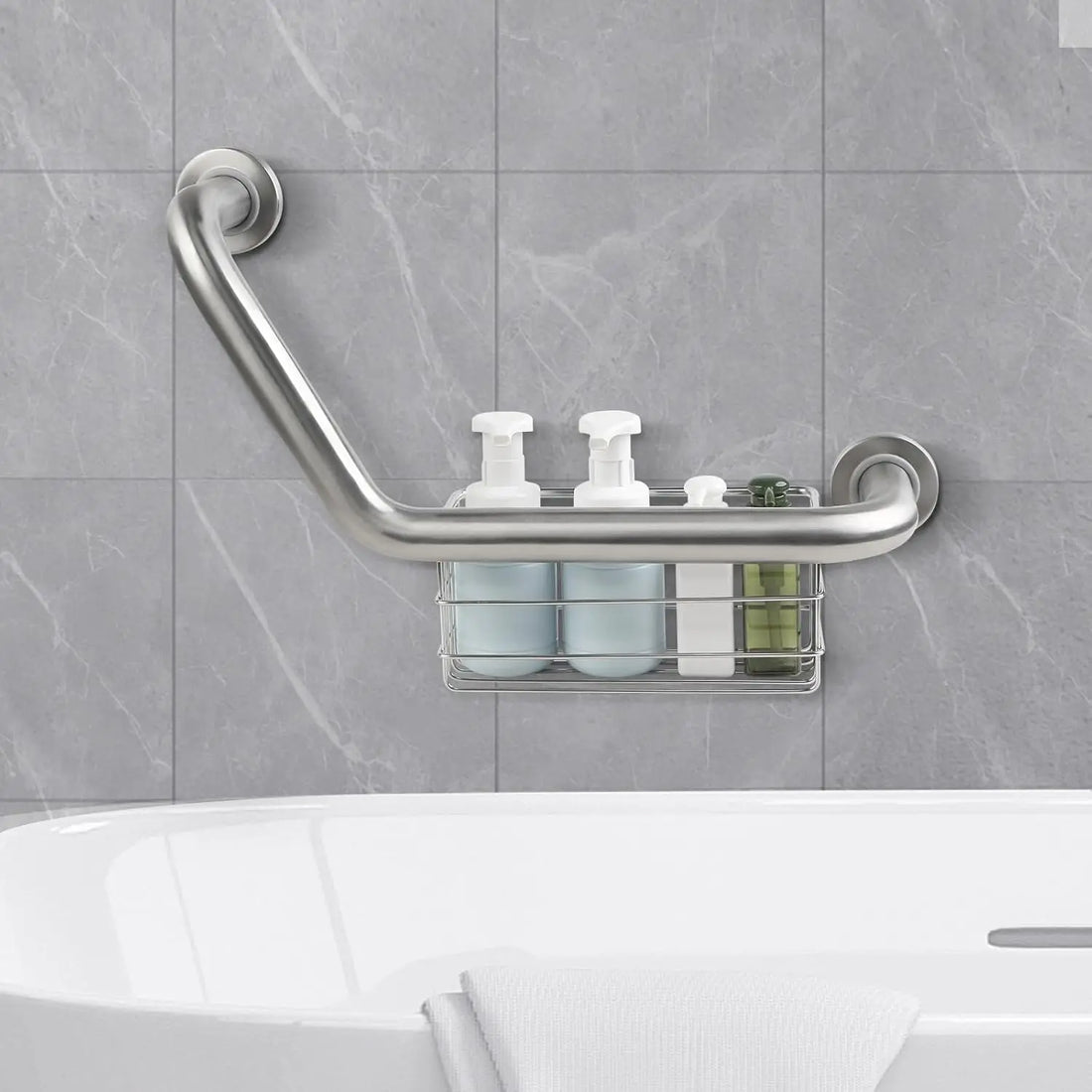 Silver angled grab bar mounted above a bathtub on gray tile, with the integrated wire basket holding shampoo and other toiletries.