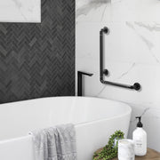 Black L-shaped bathroom grab bar installed on a tiled wall beside a bathtub, showing the vertical and horizontal support rails in a modern bathroom.